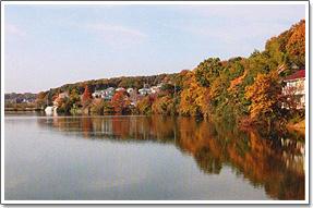 紅葉で色づいた木々が湖面に映る百穴湖（大沼）の写真
