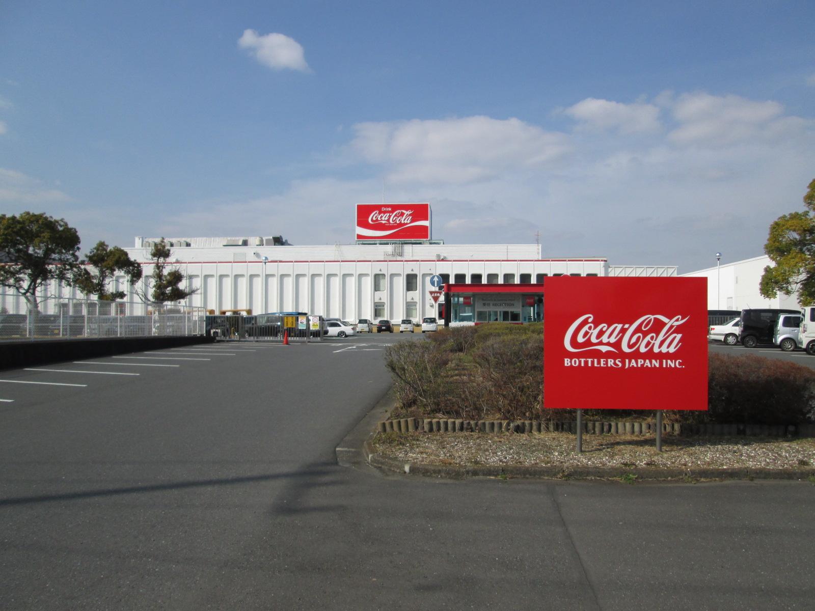 アスファルトできれいに舗装された広い敷地に建つコカ・コーラボストラーズジャパンの会社外観の写真